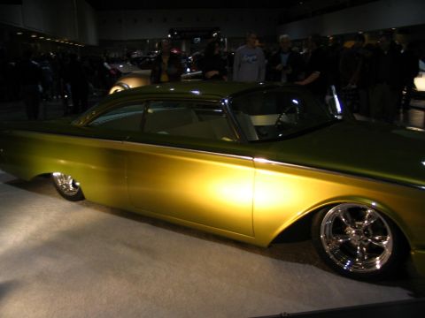 1993 Ford Taurus - A heavily modified classic car with a two-tone paint job and custom wheels is displayed indoors.