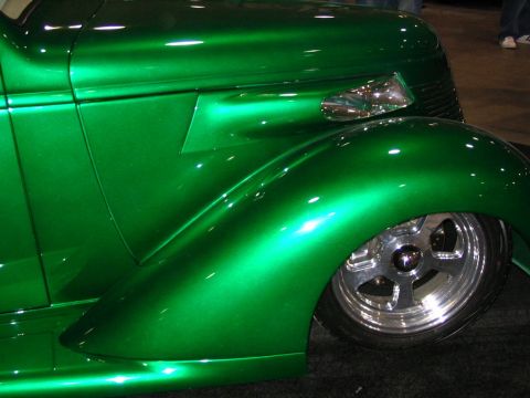 1993 Ford Taurus - Close-up of a custom green hot rod's fender and wheel, its metallic paint and chrome accents.