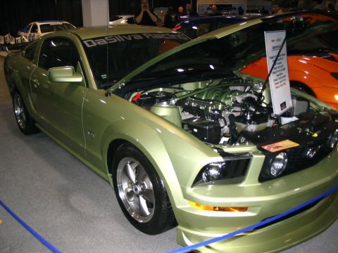 1993 Ford Taurus - A green 2005 Ford Mustang is displayed with its hood open, revealing the engine and a sign detailing its specifications.