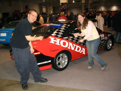 1993 Ford Taurus - Two people pose with a Honda race car at an indoor event.