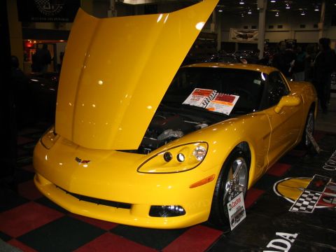 1993 Ford Taurus - A yellow Chevrolet Corvette is on display with its hood open, revealing the engine compartment.