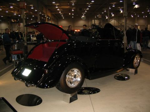 1993 Ford Taurus - Black convertible hot rod with red interior on display at an indoor event.