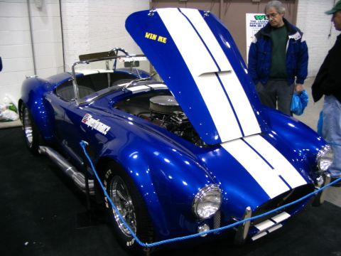 1993 Ford Taurus - A blue convertible with white racing stripes is displayed with its hood open, revealing the engine.