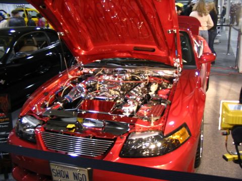 1993 Ford Taurus - A red car with flame decals and a highly customized engine bay is displayed indoors.