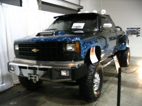 1993 Ford Taurus - Custom blue pickup truck with flame graphics and a heavy-duty bumper is displayed indoors.