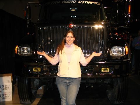 1993 Ford Taurus - A woman poses in front of a large black truck with "METRO AUDIO DYNAMICS" written above the windshield.