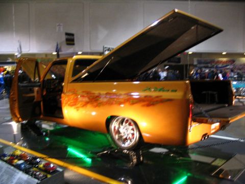 1993 Ford Taurus - This modified pickup truck features custom paint and lighting, displayed indoors at a show.