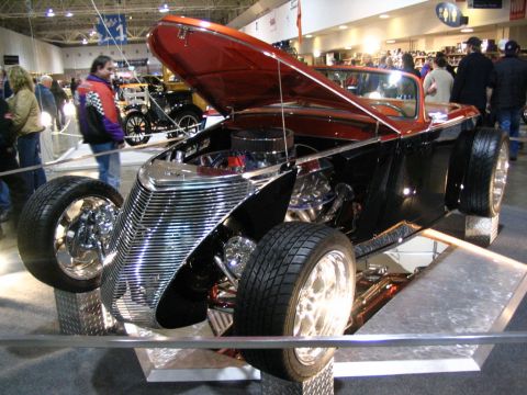 1993 Ford Taurus - Custom hot rod displayed at an indoor event, showing off its engine and unique grille design.
