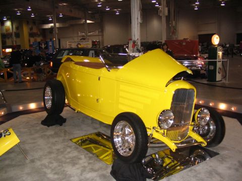 1993 Ford Taurus - A bright yellow hot rod is displayed indoors with its hood up, its custom build.