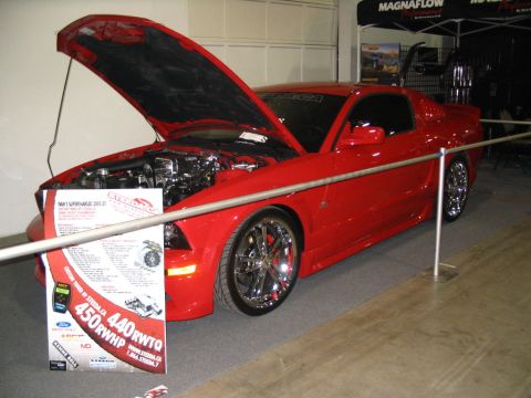 1993 Ford Taurus - Red coupe on display with its hood open, revealing the engine and a sign indicating 450 RWHP.