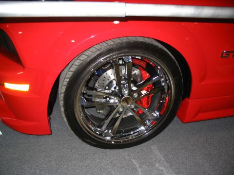 1993 Ford Taurus - Close-up of a red car's wheel and fender, showing custom chrome wheels and performance brakes.