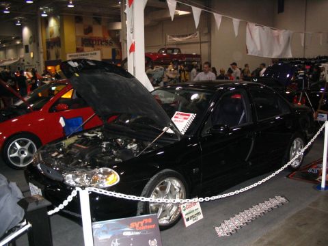 1993 Ford Taurus - A black sedan, identified as an SVT '98 Contour, is displayed with its hood open at a car show.