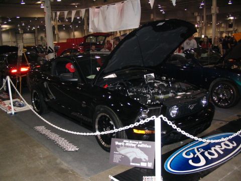 1993 Ford Taurus - A black 2006 Ford Mustang GT 'Dark Horse' edition is displayed with its hood open at a car show.