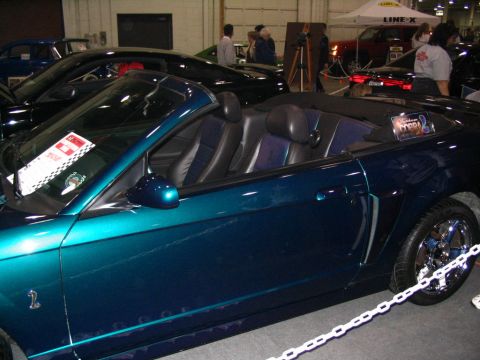 1993 Ford Taurus - This convertible Mustang features a teal paint job and a black interior, seen at an indoor car show.