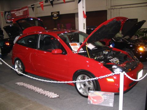 1993 Ford Taurus - A red hatchback is displayed with its engine and trunk open at an indoor event.