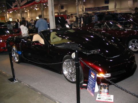 1993 Ford Taurus - A customized black convertible sports car is displayed indoors with other vehicles.