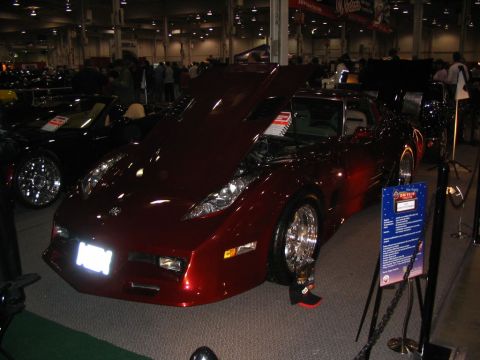 1993 Ford Taurus - A red sports car is displayed indoors with its hood open.