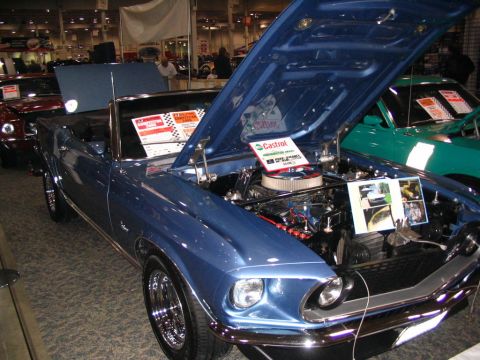 1993 Ford Taurus - A blue 1969 Ford Mustang convertible is displayed with its hood open, revealing the engine and information cards.