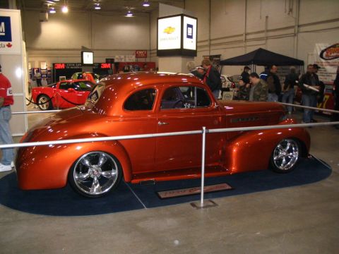 1993 Ford Taurus - Custom hot rod coupe with chrome wheels and custom paint is on display at an auto show.