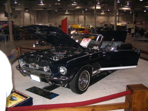 1993 Ford Taurus - A classic convertible is showcased with its engine exposed at an indoor event.