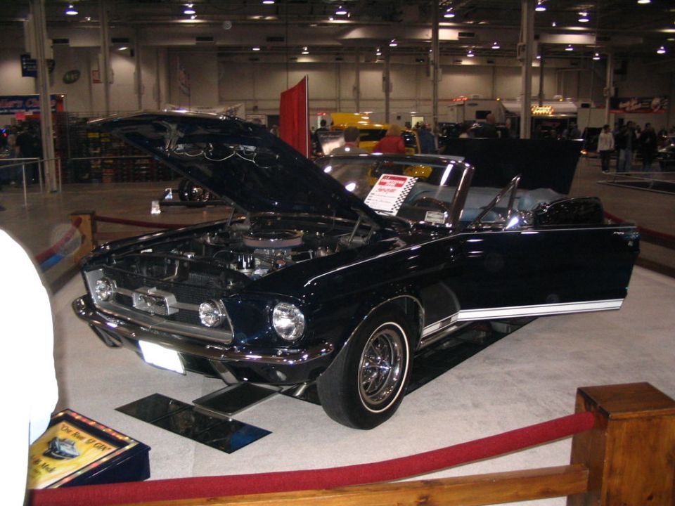 Dark blue 1967 Ford Mustang convertible with hood open, on display indoors