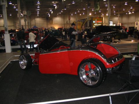 1993 Ford Taurus - A custom red convertible with large chrome wheels is displayed indoors, likely at a car show.