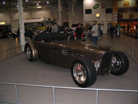 1993 Ford Taurus - A custom hot rod convertible is displayed indoors at a car show.