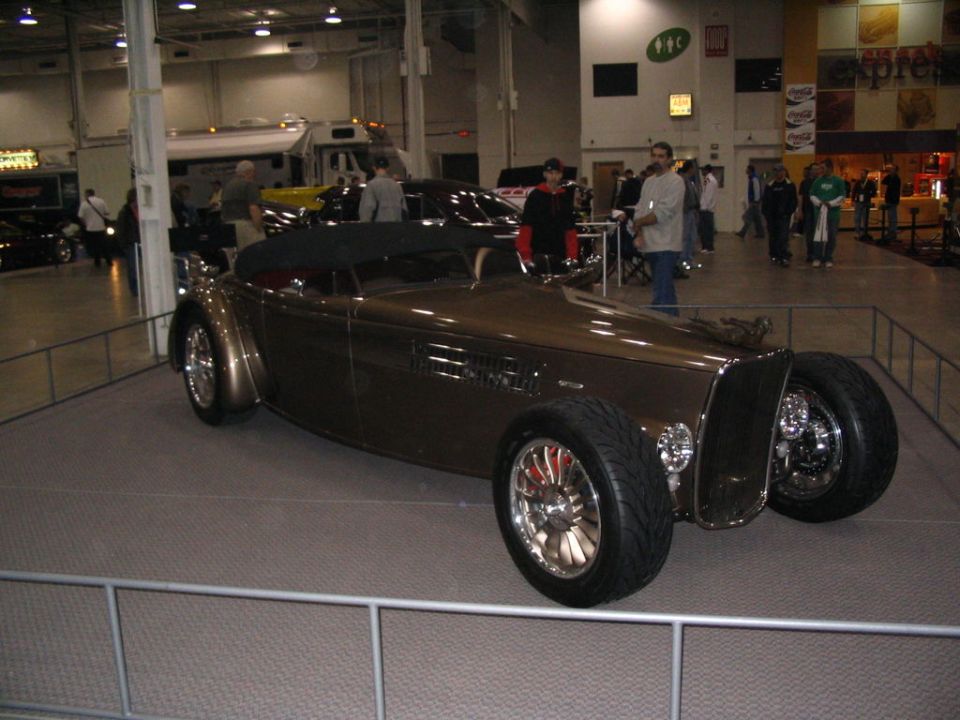 Brown custom hot rod convertible with black top, chrome wheels, and exposed engine components