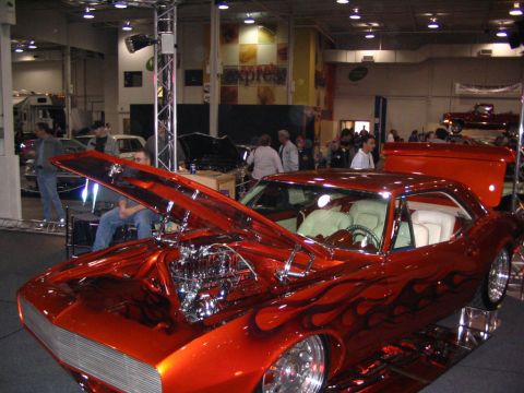 1993 Ford Taurus - Customized classic car with a bright orange flame paint job and exposed engine is displayed indoors.