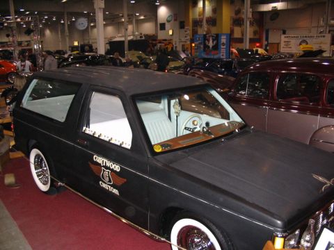 1993 Ford Taurus - A black custom SUV with whitewall tires and a 'Curtwood Custom' decal is displayed indoors among other vehicles.