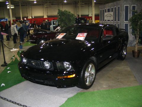 1993 Ford Taurus - A black Ford Mustang is showcased indoors, with a maroon car visible in the background.