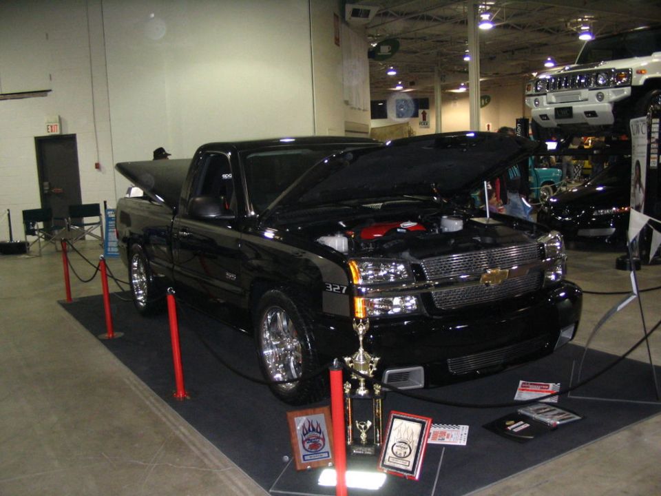 Black Chevrolet pickup truck with hood open, chrome wheels, and trophies