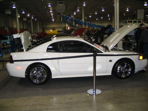1993 Ford Taurus - A white Ford Mustang is displayed with its hood and trunk open at an indoor event.