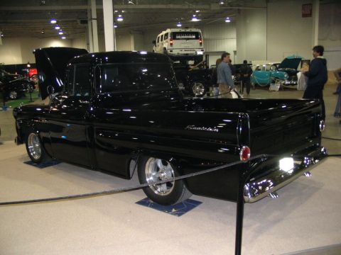 1993 Ford Taurus - Customized black pickup truck on display at a show, with other vehicles visible in the background.