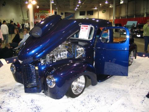 1993 Ford Taurus - A custom blue pickup truck with flames and an open hood is displayed indoors.