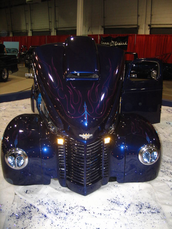 Dark blue custom hot rod with purple flames painted on the hood and fenders. Chrome grille and headlights
