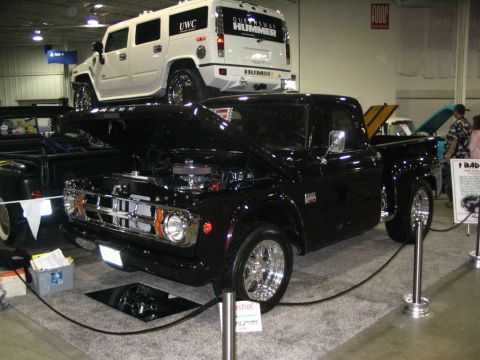 1993 Ford Taurus - A black pickup truck is displayed with its hood open, while a white Hummer SUV is elevated above it.