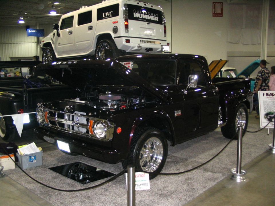 black pickup truck with hood open, white Hummer SUV on top