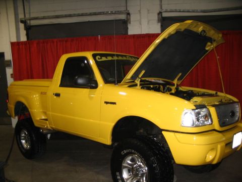1993 Ford Taurus - This yellow Ford Ranger pickup truck has a lifted suspension and its hood is open, revealing the engine compartment.