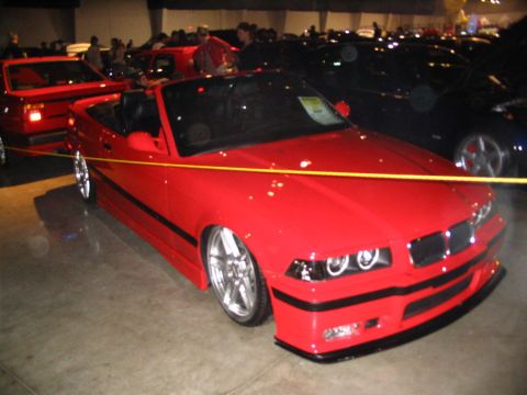 1993 Ford Taurus - A bright red convertible is displayed indoors with other vehicles in the background.