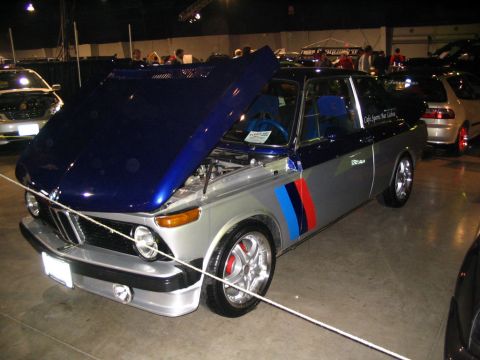 1993 Ford Taurus - A modified BMW 2002 is displayed indoors with its hood up, showing off its engine bay.