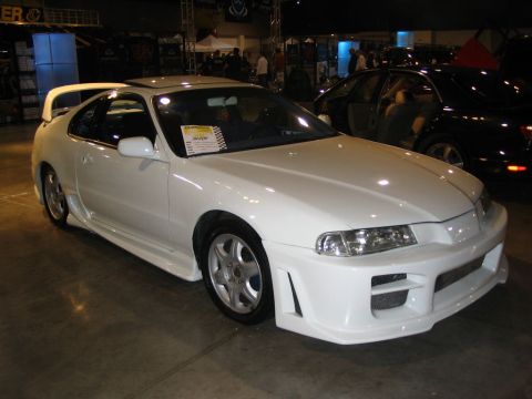 1993 Ford Taurus - A white sports coupe with custom bodywork is displayed indoors, with another car visible behind it.