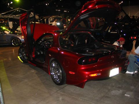 1993 Ford Taurus - A custom red sports car with its doors and hood open is displayed indoors, with other vehicles visible in the background.