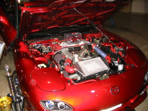 1993 Ford Taurus - A modified red Mazda RX-7 is displayed with its hood open, revealing a custom rotary engine setup.