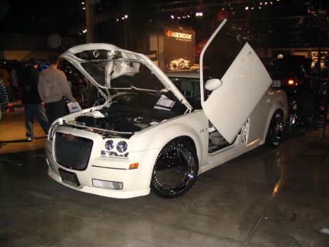 1993 Ford Taurus - White Chrysler 300 with custom grille and lambo doors displayed at a show.