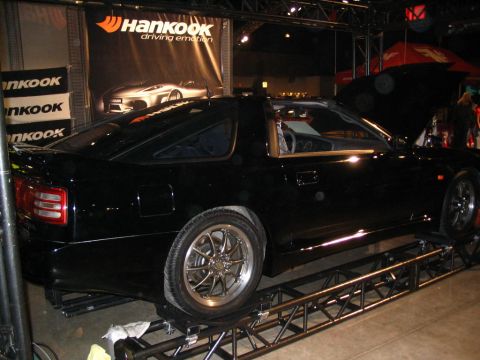 1993 Ford Taurus - A black sports coupe is displayed on a metal stand with a Hankook banner behind it.