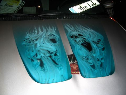 1993 Ford Taurus - Custom airbrushed hood features a design of multiple skulls engulfed in flames, rendered in shades of blue and white.