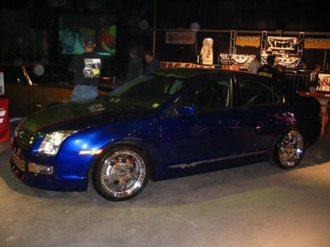 1993 Ford Taurus - This blue sedan, likely a 2006 model, is displayed with custom chrome wheels and a modified front end.