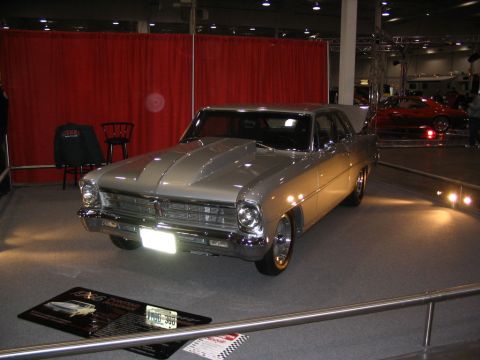 1993 Ford Taurus - A silver 1966 Chevrolet Nova is displayed at a car show, with a red car visible in the background.