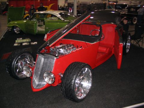 1993 Ford Taurus - A red custom hot rod and a green and white classic car are displayed indoors.